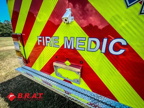 Exterior view of small fire truck showing cab, body compartments, and wheel/tire area.