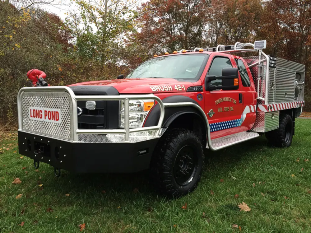 Exterior view of small fire truck showing cab, body compartments, and wheel/tire area.