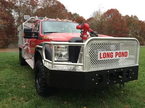 Exterior view of small fire truck showing cab, body compartments, and wheel/tire area.