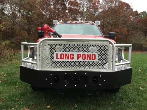 Exterior view of small fire truck showing cab, body compartments, and wheel/tire area.
