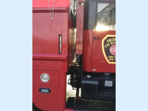 Exterior view of small fire truck showing cab, body compartments, and wheel/tire area.