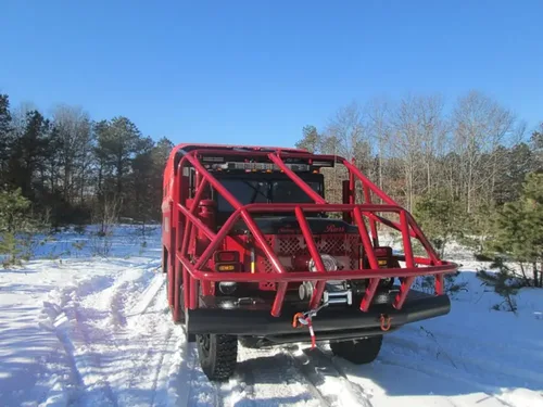 Exterior view of small fire truck showing cab, body compartments, and wheel/tire area.