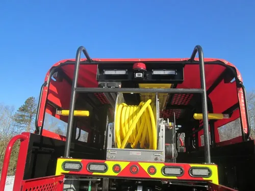 Exterior view of small fire truck showing cab, body compartments, and wheel/tire area.