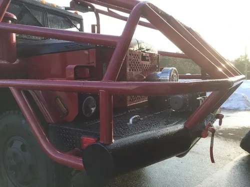 Exterior view of small fire truck showing cab, body compartments, and wheel/tire area.