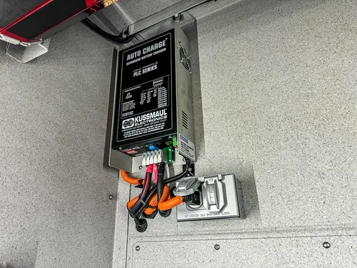 Side compartment wall with mounted battery charger and outlet box.