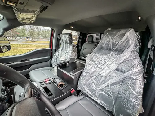 Passenger-side interior with front and rear seats wrapped in plastic.