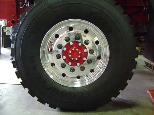 Exterior view of small fire truck showing cab, body compartments, and wheel/tire area.