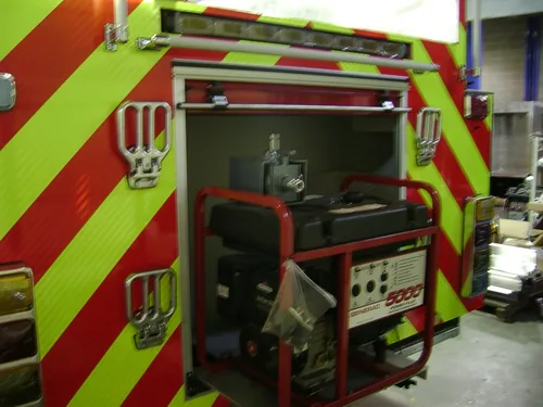 Exterior view of small fire truck showing cab, body compartments, and wheel/tire area.