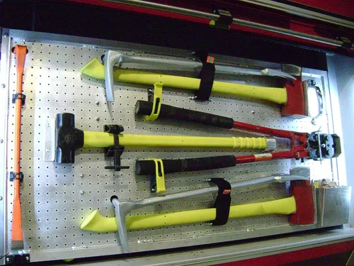 Exterior view of small fire truck showing cab, body compartments, and wheel/tire area.