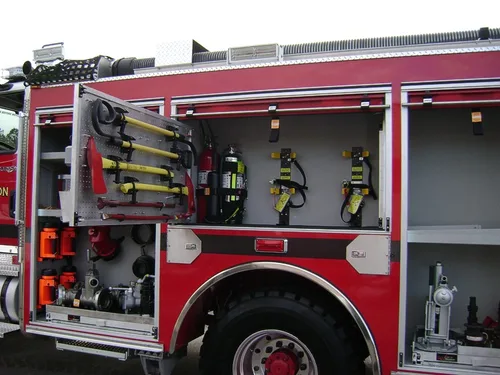 Exterior view of small fire truck showing cab, body compartments, and wheel/tire area.