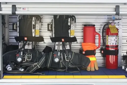 Exterior view of small fire truck showing cab, body compartments, and wheel/tire area.