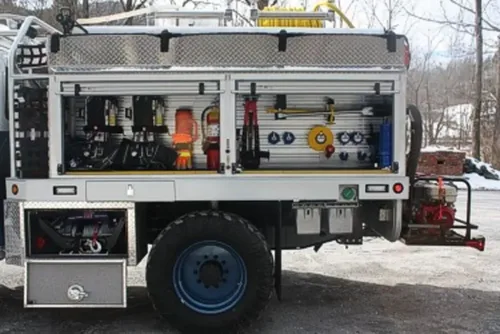 Exterior view of small fire truck showing cab, body compartments, and wheel/tire area.