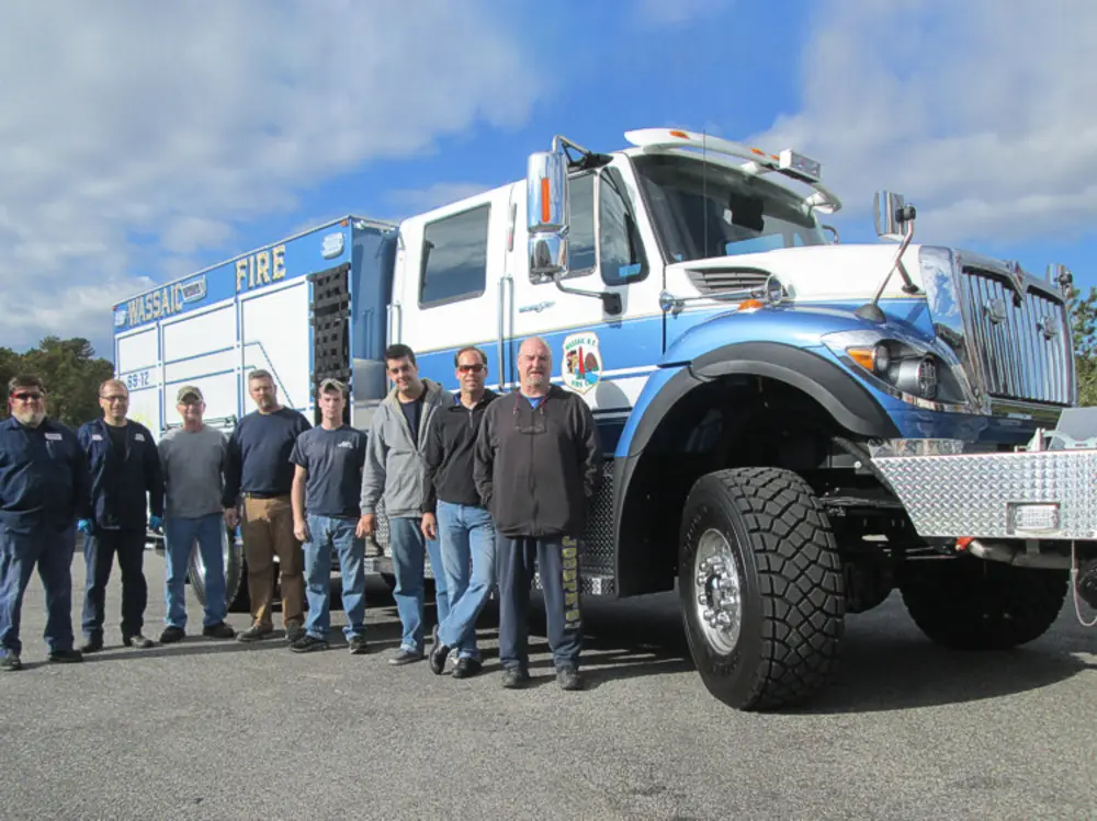 Exterior view of small fire truck showing cab, body compartments, and wheel/tire area.