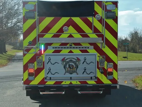 Exterior view of small fire truck showing cab, body compartments, and wheel/tire area.