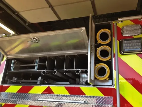 Exterior view of small fire truck showing cab, body compartments, and wheel/tire area.