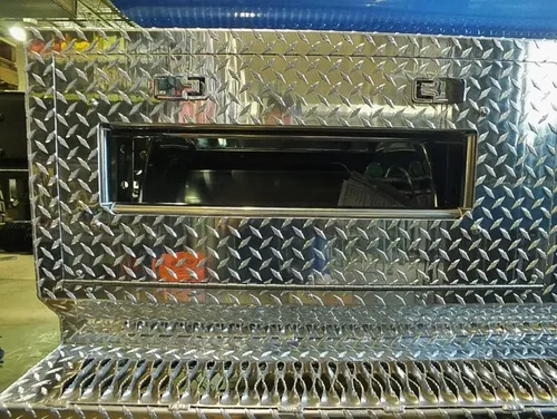 Exterior view of small fire truck showing cab, body compartments, and wheel/tire area.