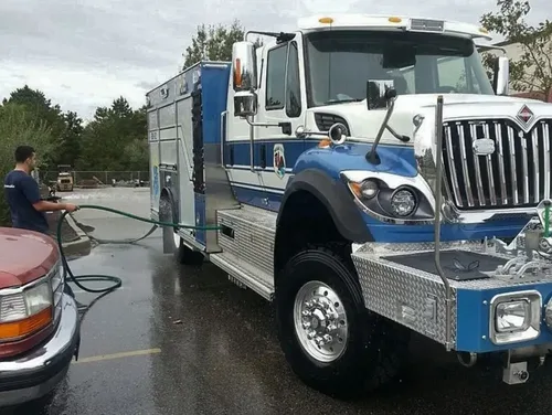 Exterior view of small fire truck showing cab, body compartments, and wheel/tire area.