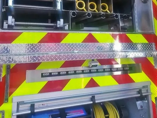 Exterior view of small fire truck showing cab, body compartments, and wheel/tire area.