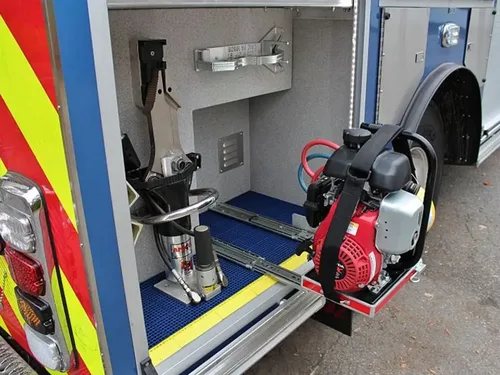 Exterior view of small fire truck showing cab, body compartments, and wheel/tire area.
