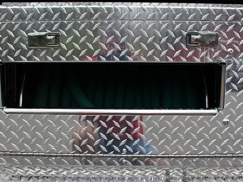 Exterior view of small fire truck showing cab, body compartments, and wheel/tire area.