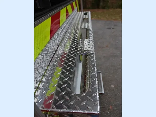 Exterior view of small fire truck showing cab, body compartments, and wheel/tire area.