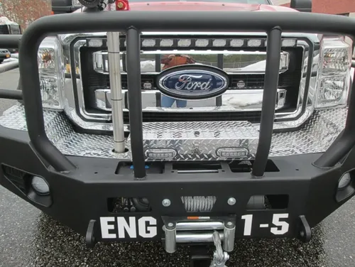 Exterior view of small fire truck showing cab, body compartments, and wheel/tire area.