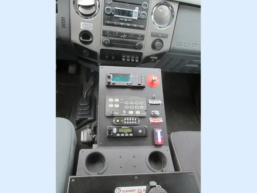 Exterior view of small fire truck showing cab, body compartments, and wheel/tire area.