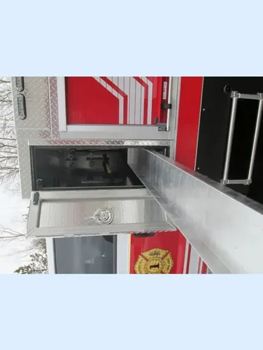 Exterior view of small fire truck showing cab, body compartments, and wheel/tire area.