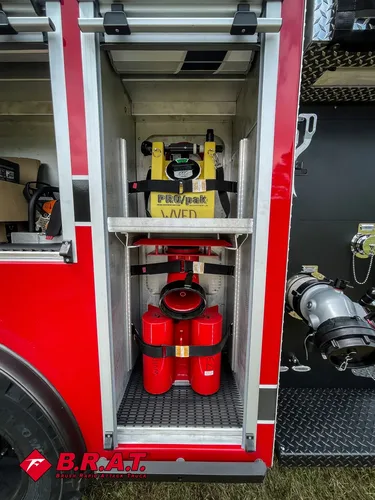 Open narrow compartment with red nozzle and yellow portable power unit.