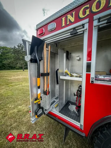 Open side compartment with mounted long-handled tools and shelving.