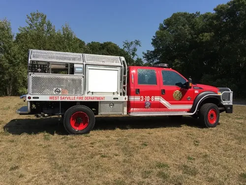 Exterior view of small fire truck showing cab, body compartments, and wheel/tire area.