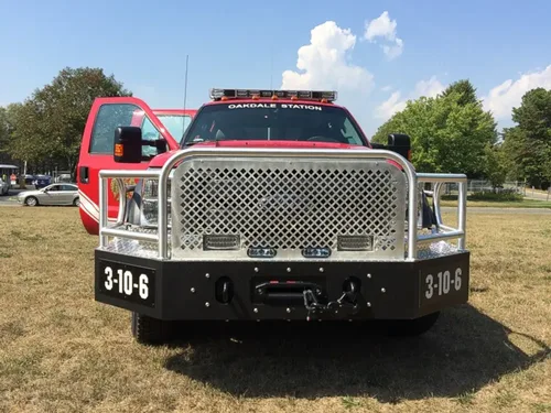 Exterior view of small fire truck showing cab, body compartments, and wheel/tire area.