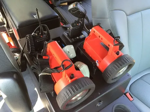 Exterior view of small fire truck showing cab, body compartments, and wheel/tire area.
