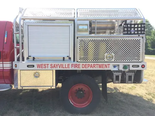 Exterior view of small fire truck showing cab, body compartments, and wheel/tire area.