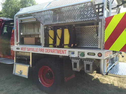 Exterior view of small fire truck showing cab, body compartments, and wheel/tire area.