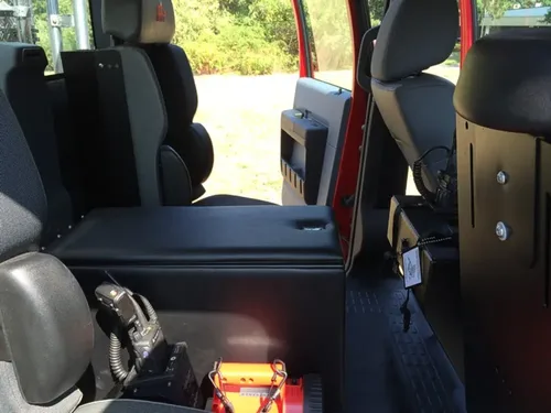 Exterior view of small fire truck showing cab, body compartments, and wheel/tire area.