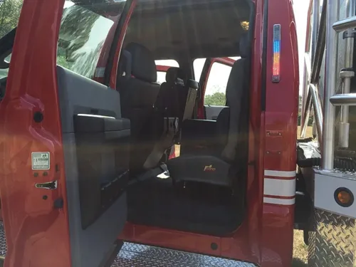 Exterior view of small fire truck showing cab, body compartments, and wheel/tire area.