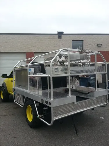 Exterior view of small fire truck showing cab, body compartments, and wheel/tire area.