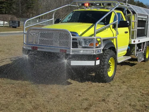 Exterior view of small fire truck showing cab, body compartments, and wheel/tire area.