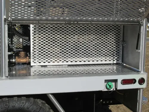 Exterior view of small fire truck showing cab, body compartments, and wheel/tire area.