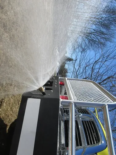 Exterior view of small fire truck showing cab, body compartments, and wheel/tire area.