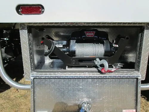 Exterior view of small fire truck showing cab, body compartments, and wheel/tire area.