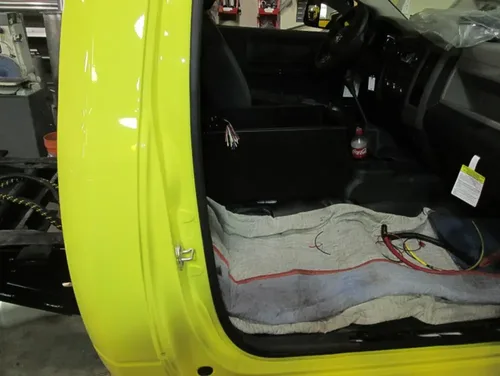 Exterior view of small fire truck showing cab, body compartments, and wheel/tire area.
