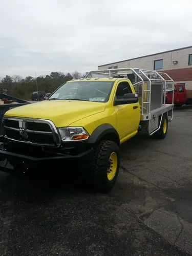 Exterior view of small fire truck showing cab, body compartments, and wheel/tire area.