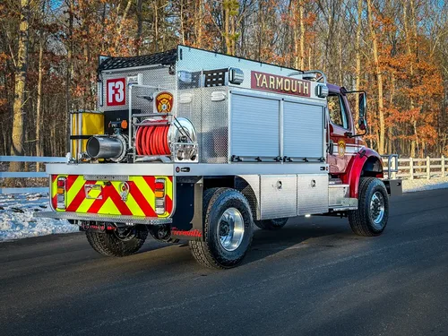 Rear-right three-quarter exterior view showing hose reel, dump chute, and rear lighting.
