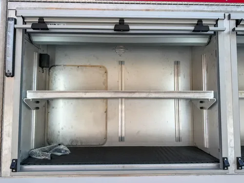 Close-up of an open upper side compartment with adjustable shelf and interior light.