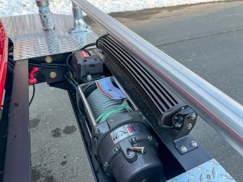 Close-up behind brush guard showing winch drum and mounted light bar.