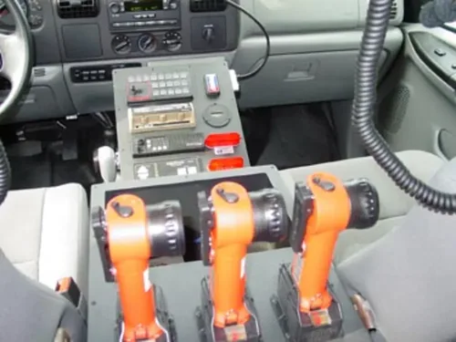 Exterior view of small fire truck showing cab, body compartments, and wheel/tire area.