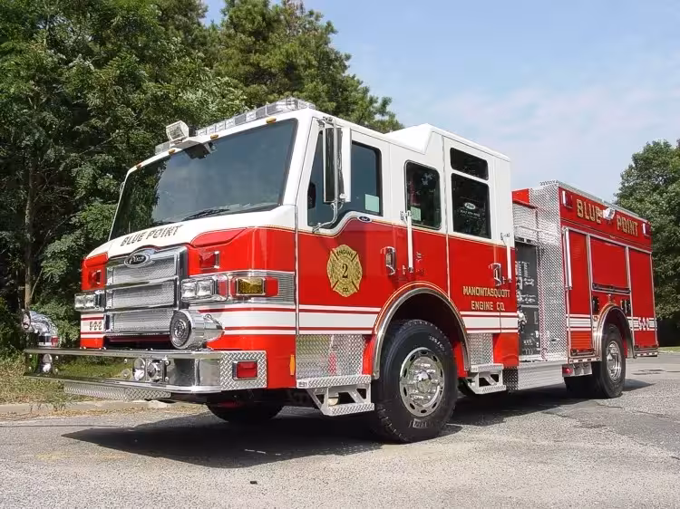 Front-right exterior view of a pumper showing the cab, bumper, pump panel section, and side compartments.