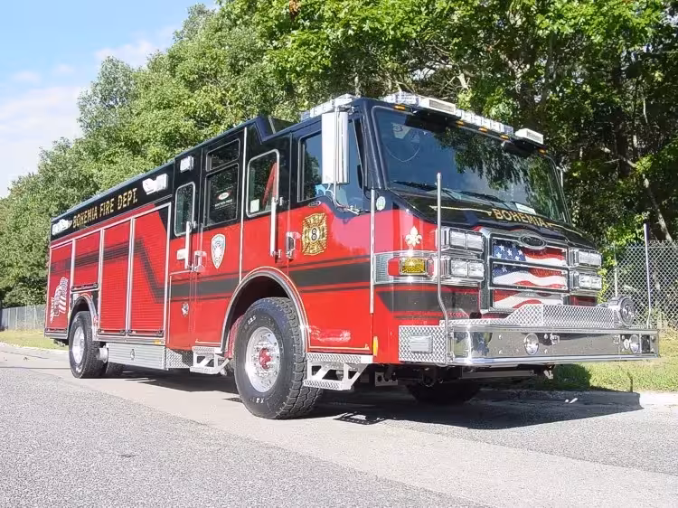 Front-right exterior view of a heavy rescue truck with enclosed cab, side compartments, and wheel/tire area.